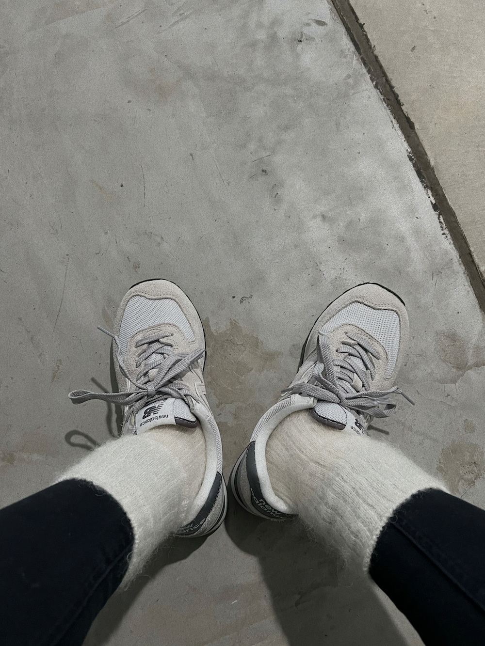 グレー系のスニーカー、ブラック系のショルダーバッグ、ホワイト系のダウンジャケット/コートを着用したレディースの冬コーディネートの3枚目の写真