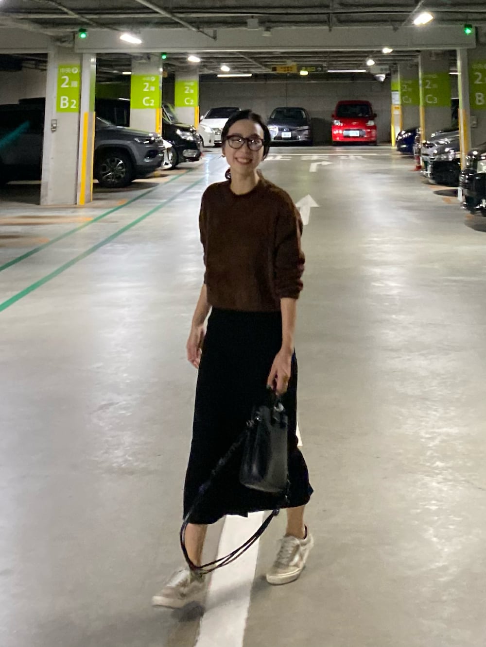 ブラック系のショルダーバッグ、ベージュ系のスニーカー、ブラウン系のニット/セーターを着用したレディースの秋コーディネートの3枚目の写真