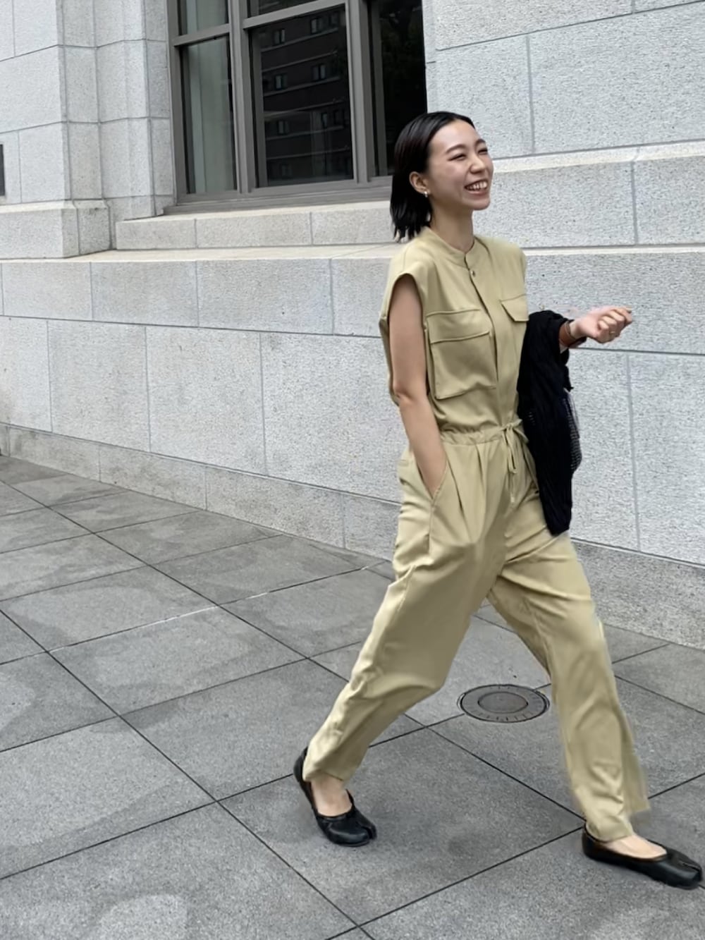 ブラック系のハンドバッグ、ベージュ系のつなぎ/オールインワンを着用したレディースの夏コーディネートの2枚目の写真
