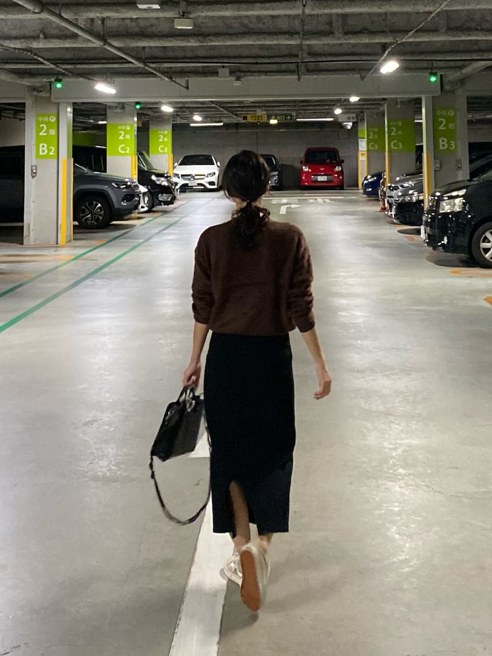 ブラック系のショルダーバッグ、ベージュ系のスニーカー、ブラウン系のニット/セーターを着用したレディースの秋コーディネートの4枚目の写真