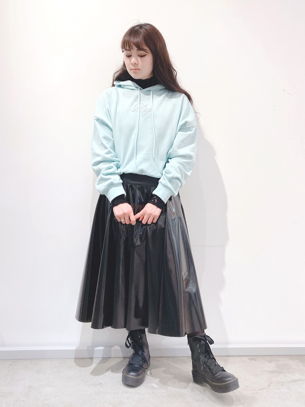 ブラック系のスカート、ピンク系のパーカー、ブラック系のブーツを着用したレディースの冬コーディネートの2枚目の写真