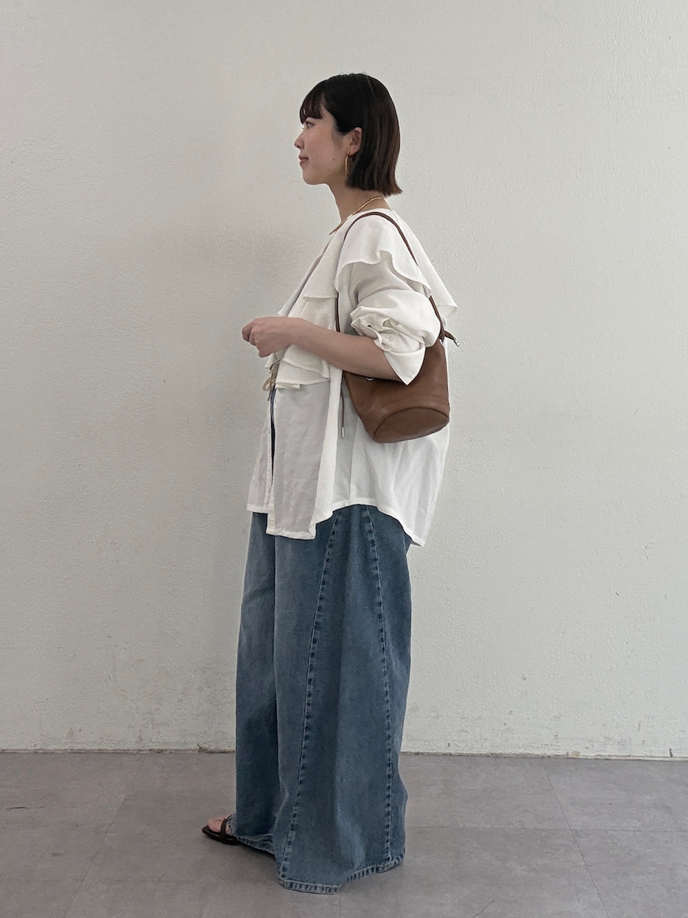 ホワイト系のシャツ/ブラウス、ブラウン系のトートバッグ、ブルー系のデニムパンツを着用したレディースの冬コーディネートの2枚目の写真