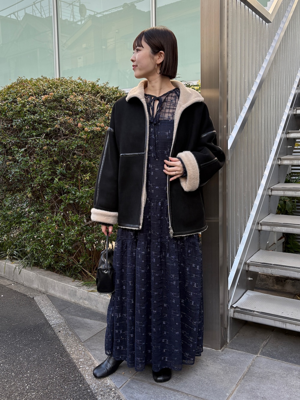 ブラック系のムートンコート、ブルー系のワンピース、ブラック系のブーツを着用したレディースの冬コーディネートの2枚目の写真