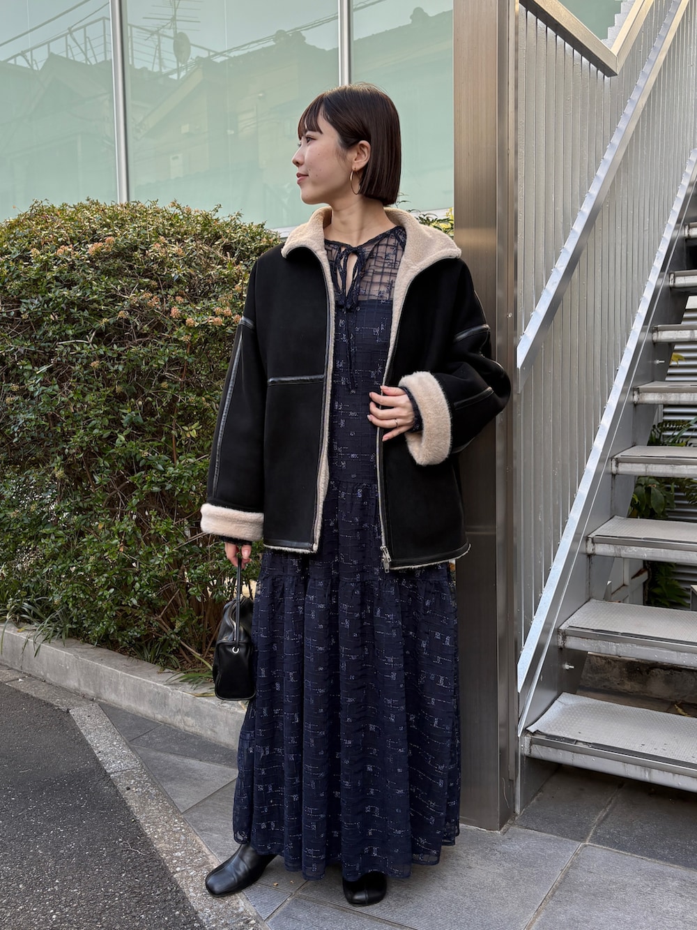 ブラック系のムートンコート、ブラック系のブーツ、ブラック系のワンピースを着用したレディースの秋コーディネートの2枚目の写真