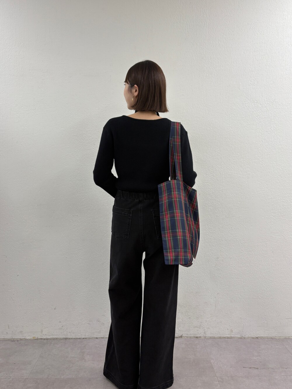 ブラック系のニット/セーター、グリーン系のトートバッグ、グレー系のデニムパンツを着用したレディースの秋コーディネートの3枚目の写真