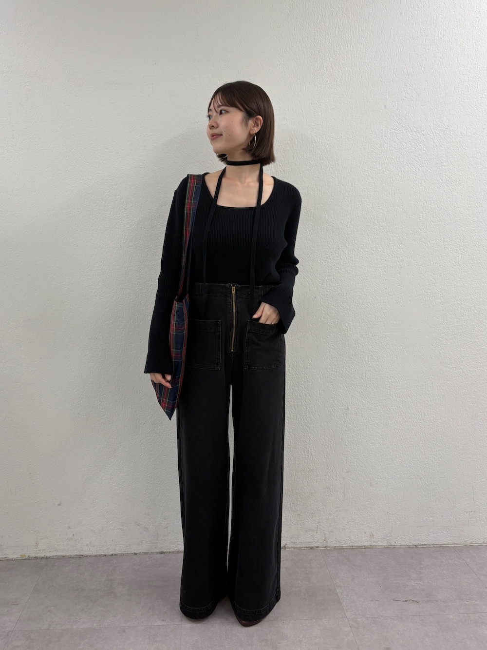 ブラック系のニット/セーター、グリーン系のトートバッグ、グレー系のデニムパンツを着用したレディースの秋コーディネートの2枚目の写真