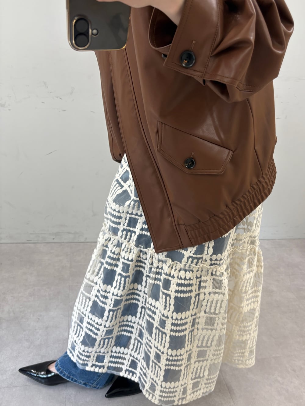 ブラウン系のブルゾン、ホワイト系のワンピース、ブルー系のデニムパンツを着用したレディースの秋コーディネートの4枚目の写真