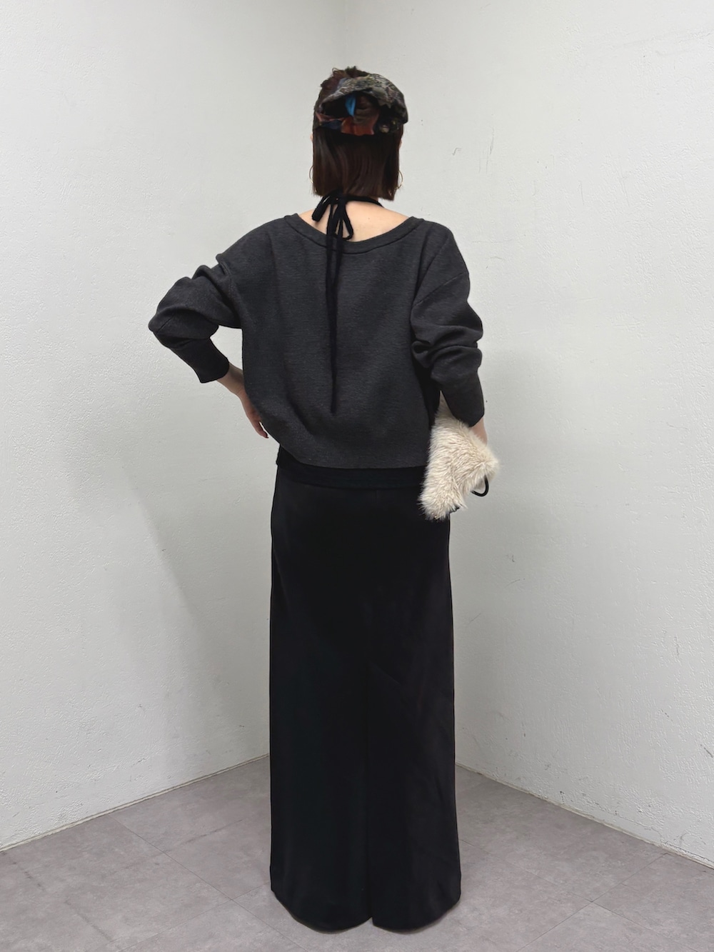 ブラック系のニット/セーター、ブラック系のスカート、ベージュ系のバックパック/リュックを着用したレディースの秋コーディネートの3枚目の写真