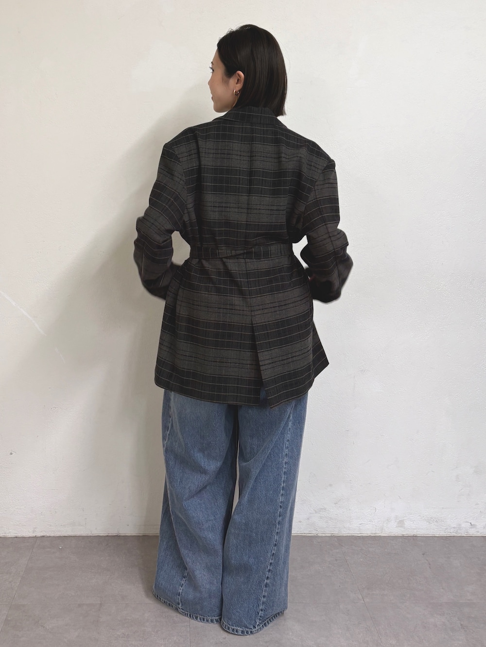 グレー系のテーラードジャケット、グレー系のTシャツ/カットソー、ブルー系のデニムパンツを着用したレディースの秋コーディネートの3枚目の写真