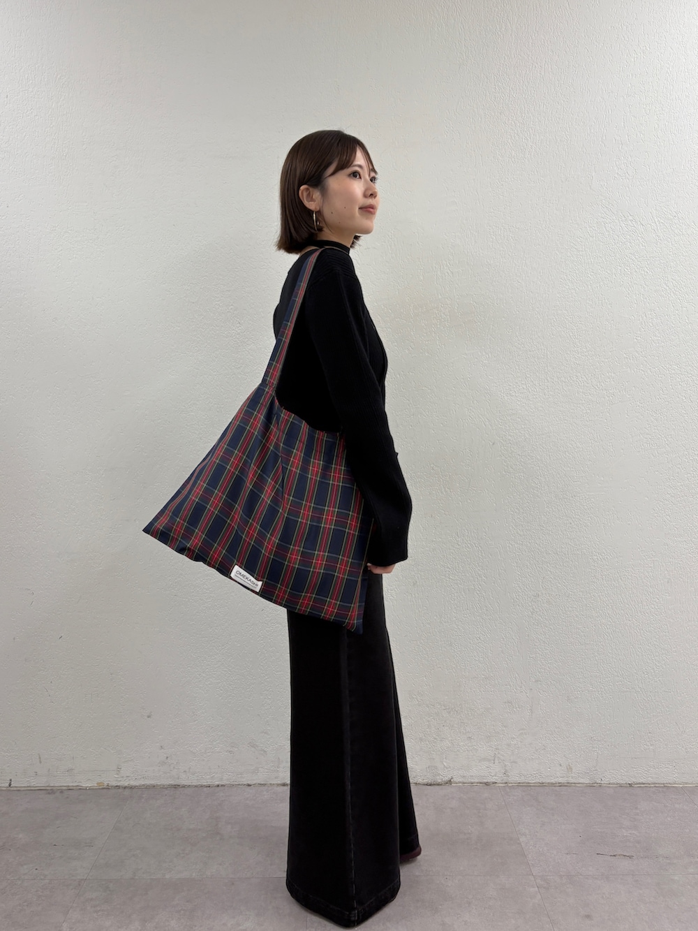 ブラック系のニット/セーター、グリーン系のトートバッグ、グレー系のデニムパンツを着用したレディースの秋コーディネートの4枚目の写真