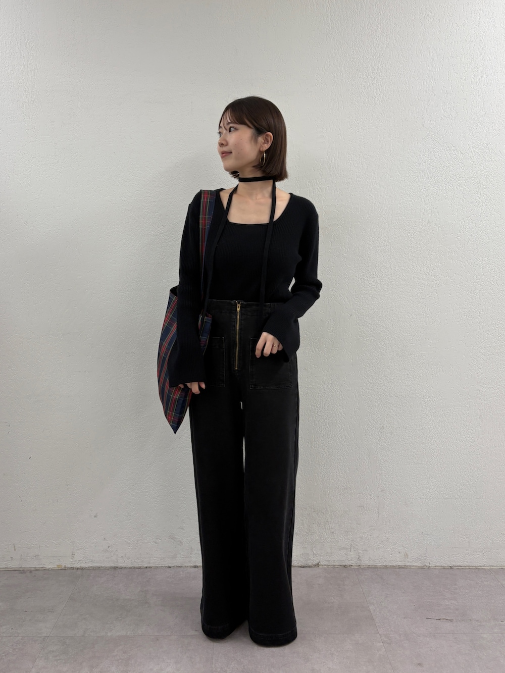 ブラック系のニット/セーター、グリーン系のトートバッグ、グレー系のデニムパンツを着用したレディースの秋コーディネートの5枚目の写真