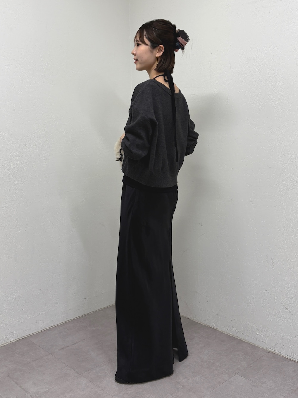 ブラック系のニット/セーター、ブラック系のスカート、ベージュ系のバックパック/リュックを着用したレディースの秋コーディネートの2枚目の写真