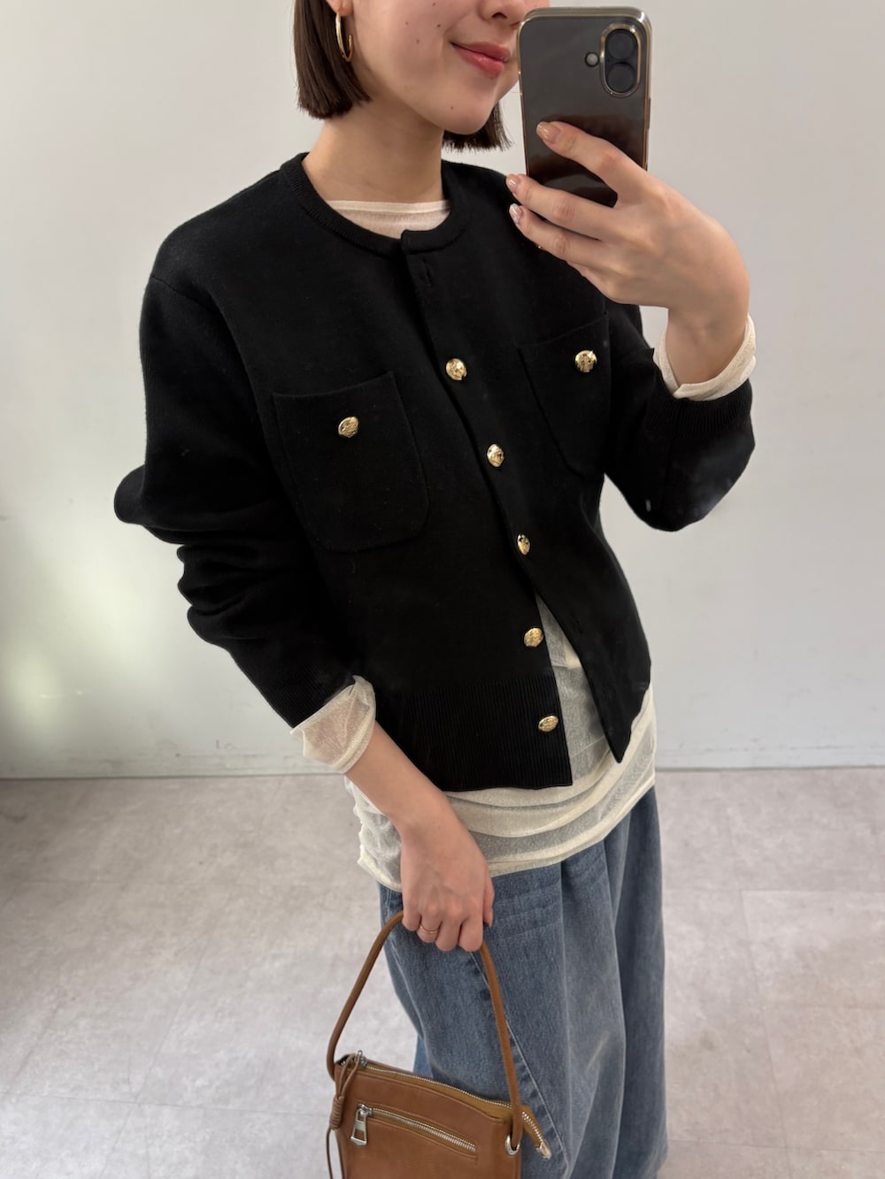 ブラック系のカーディガン/ボレロ、ホワイト系のTシャツ/カットソー、ブルー系のデニムパンツを着用したレディースの秋コーディネートの2枚目の写真