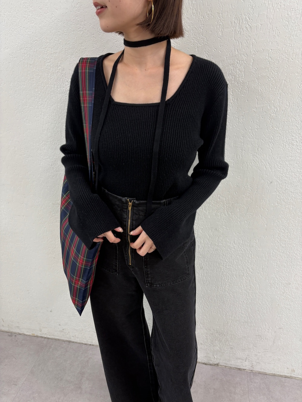 ブラック系のニット/セーター、グリーン系のトートバッグ、グレー系のデニムパンツを着用したレディースの秋コーディネートの6枚目の写真