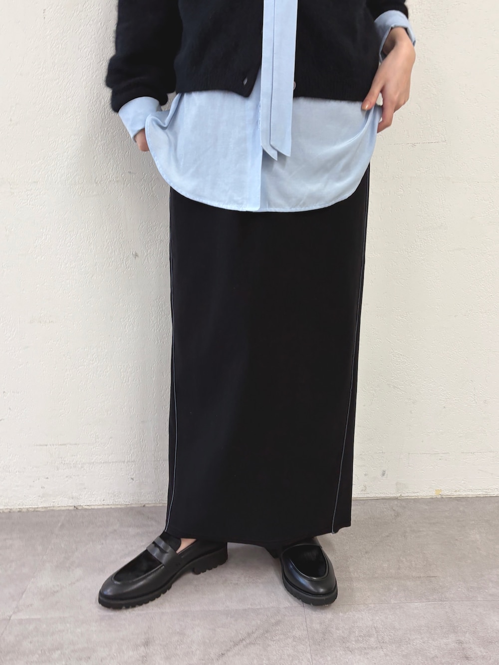 ブラック系のカーディガン/ボレロ、ブルー系のシャツ/ブラウス、ブラック系のスカートを着用したレディースの秋コーディネートの5枚目の写真