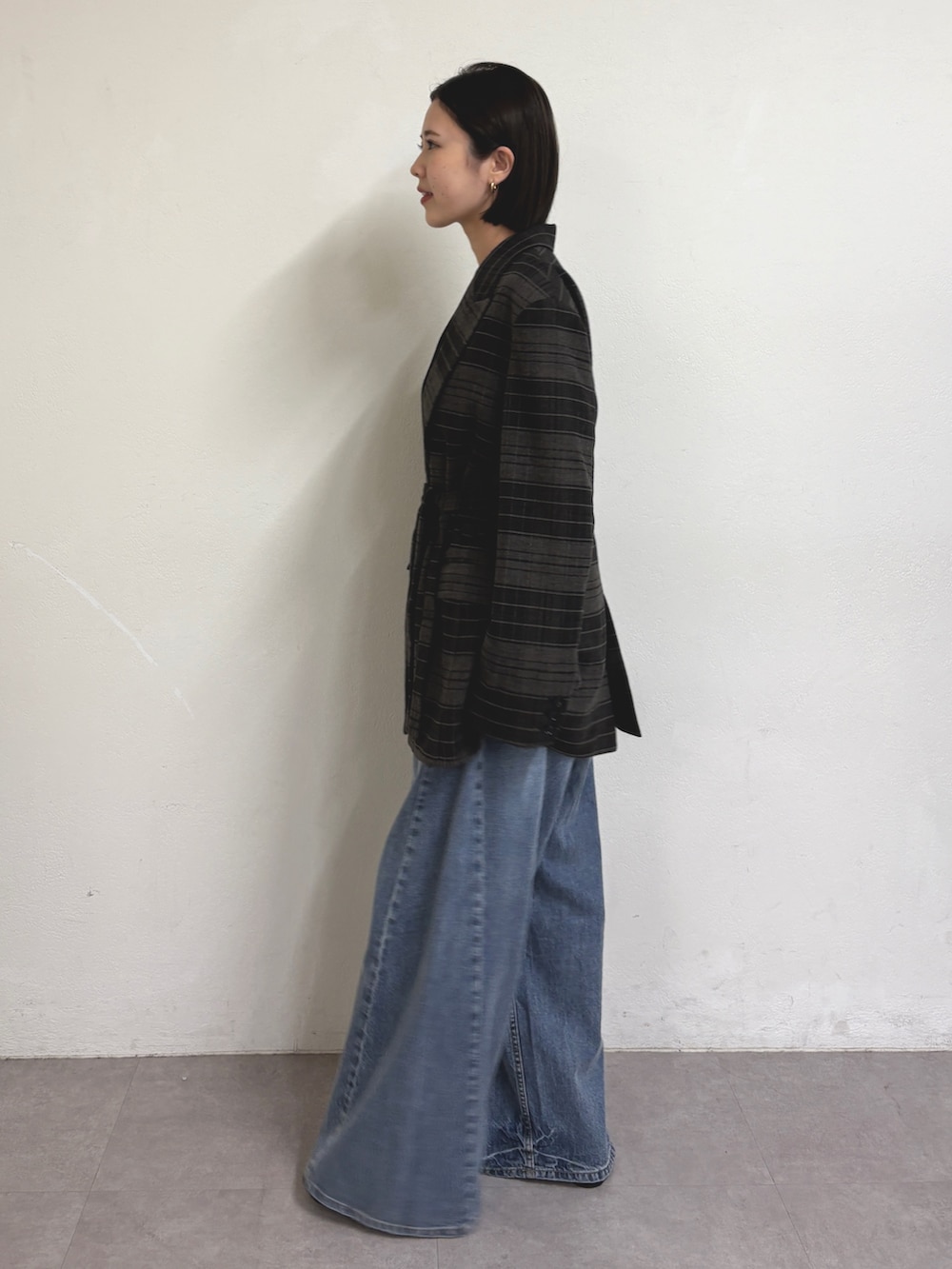 グレー系のテーラードジャケット、グレー系のTシャツ/カットソー、ブルー系のデニムパンツを着用したレディースの秋コーディネートの2枚目の写真