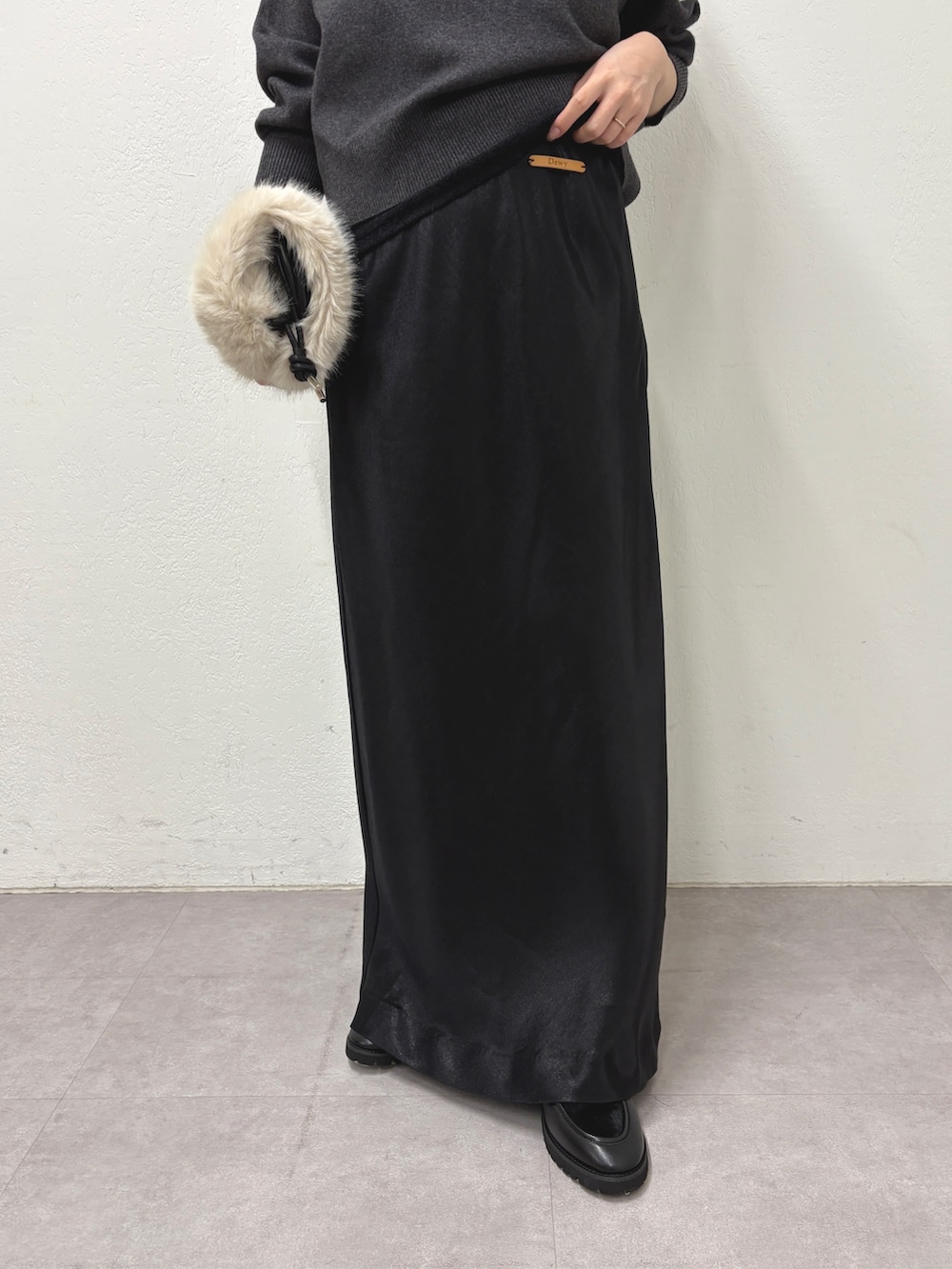 ブラック系のニット/セーター、ブラック系のスカート、ベージュ系のバックパック/リュックを着用したレディースの秋コーディネートの4枚目の写真