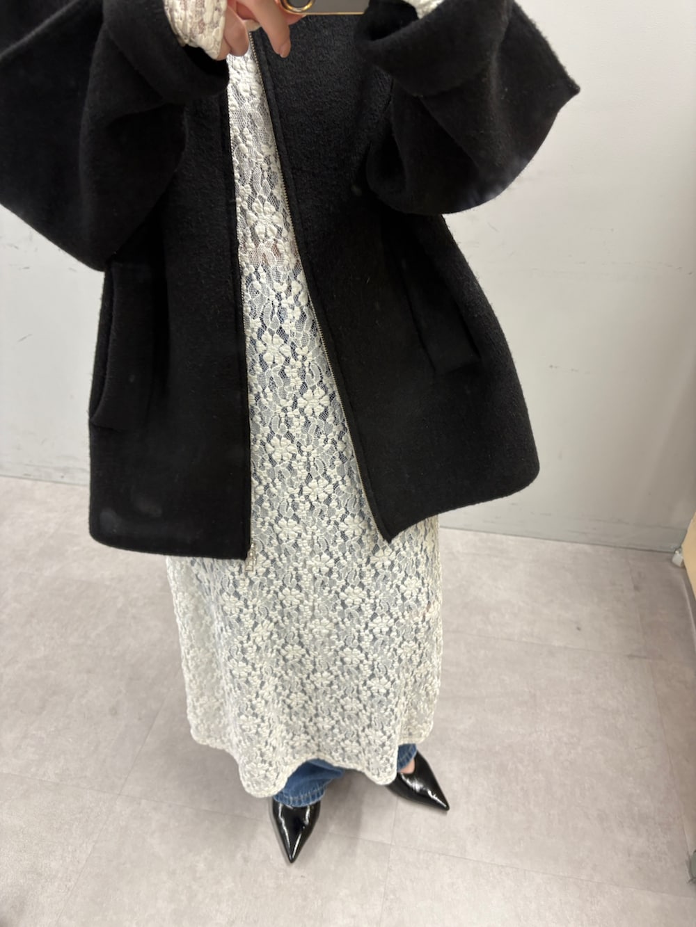 ブラック系のその他アウター、ホワイト系のワンピース、ブルー系のデニムパンツを着用したレディースの秋コーディネートの3枚目の写真