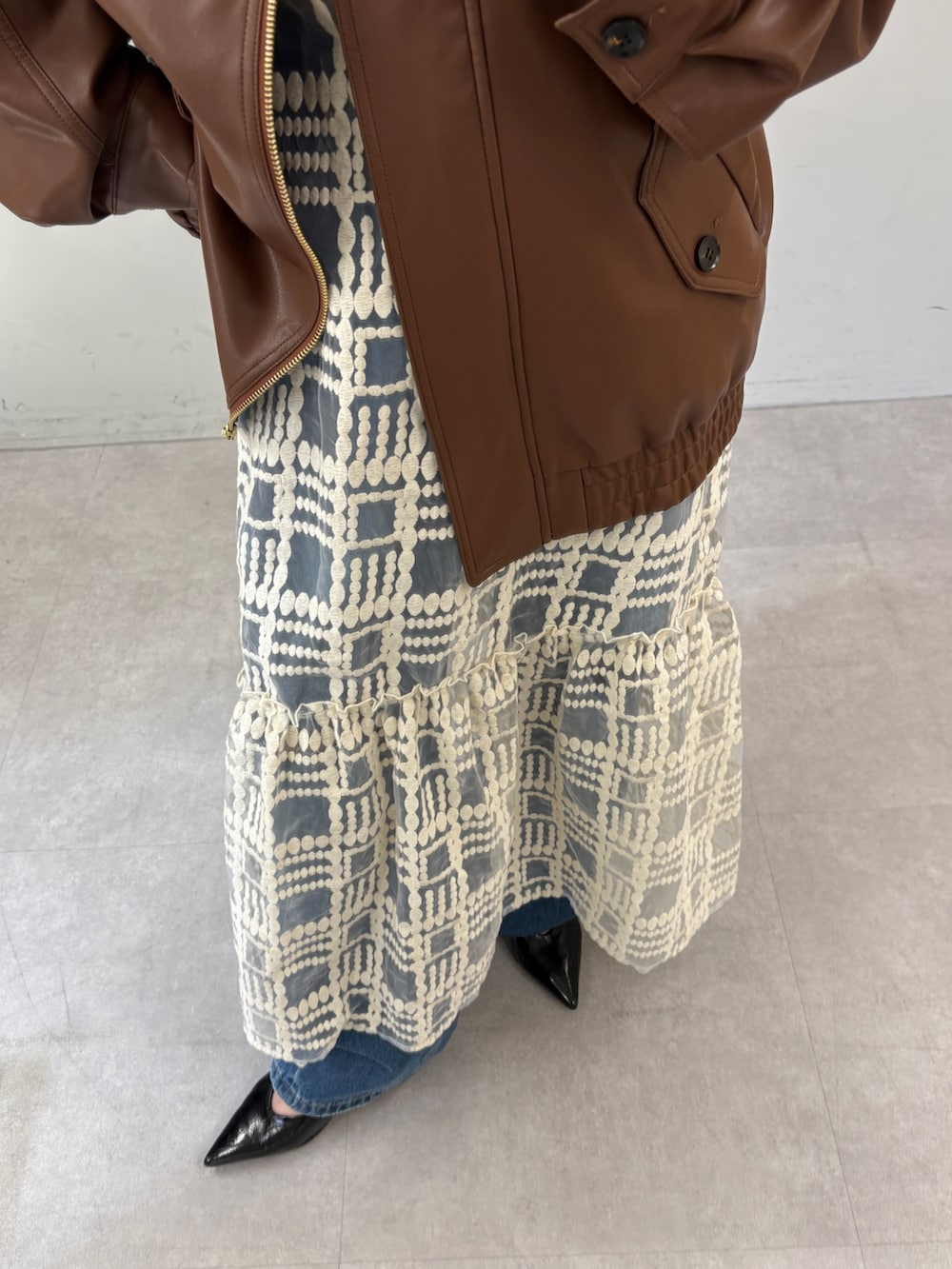 ブラウン系のブルゾン、ホワイト系のワンピース、ブルー系のデニムパンツを着用したレディースの秋コーディネートの3枚目の写真