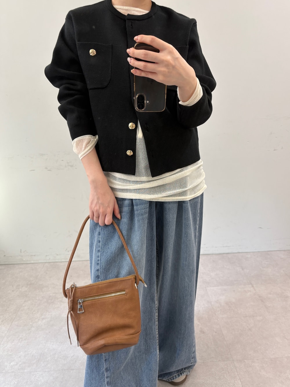 ブラック系のカーディガン/ボレロ、ホワイト系のTシャツ/カットソー、ブルー系のデニムパンツを着用したレディースの秋コーディネートの3枚目の写真