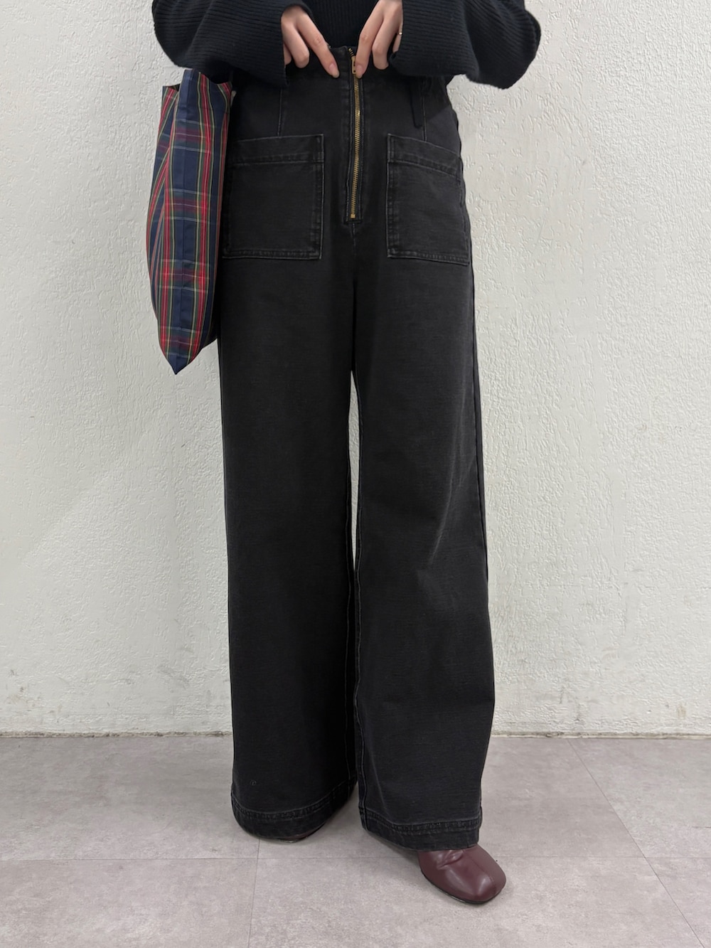 ブラック系のニット/セーター、グリーン系のトートバッグ、グレー系のデニムパンツを着用したレディースの秋コーディネートの7枚目の写真