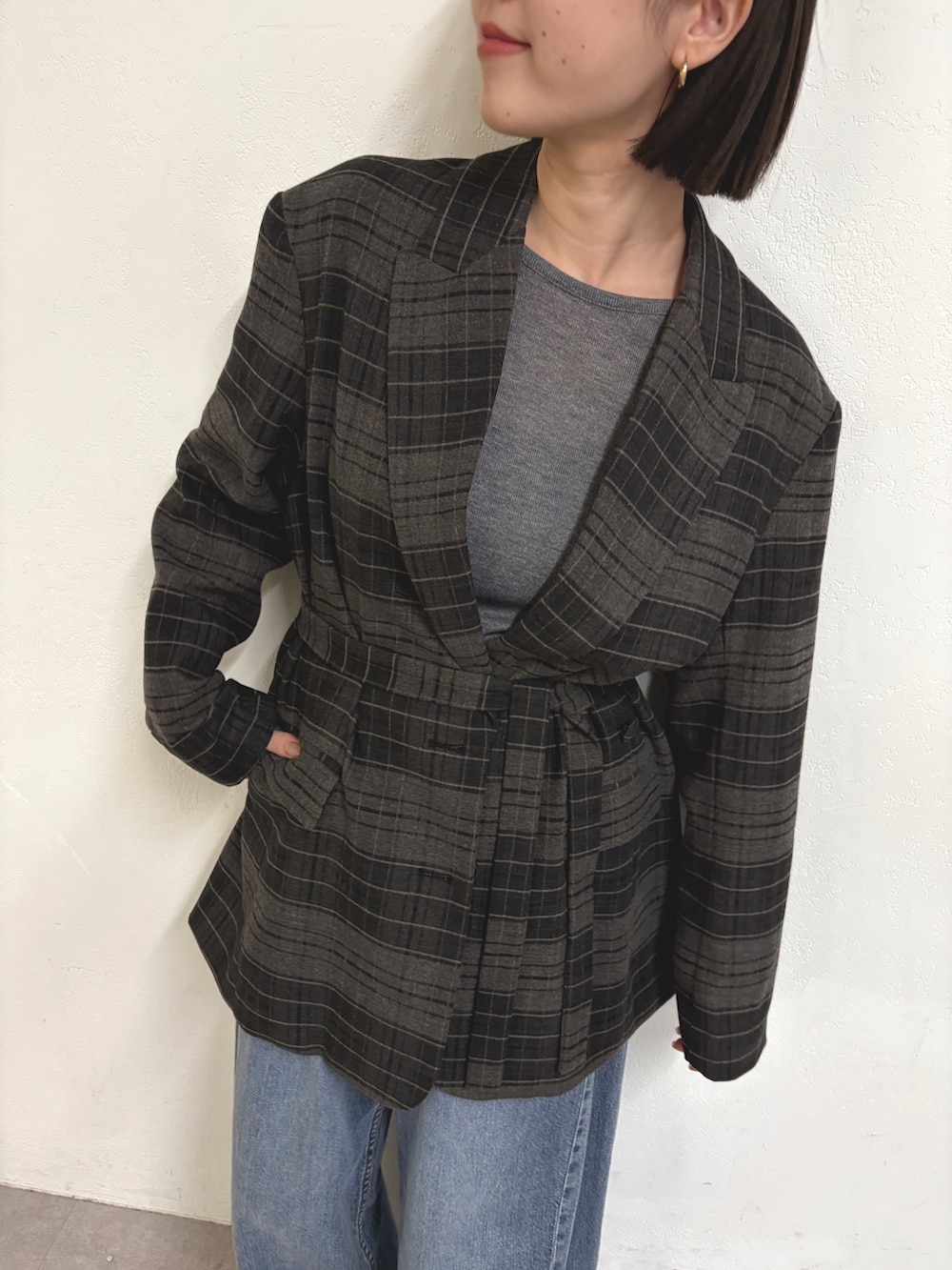 グレー系のテーラードジャケット、グレー系のTシャツ/カットソー、ブルー系のデニムパンツを着用したレディースの秋コーディネートの4枚目の写真