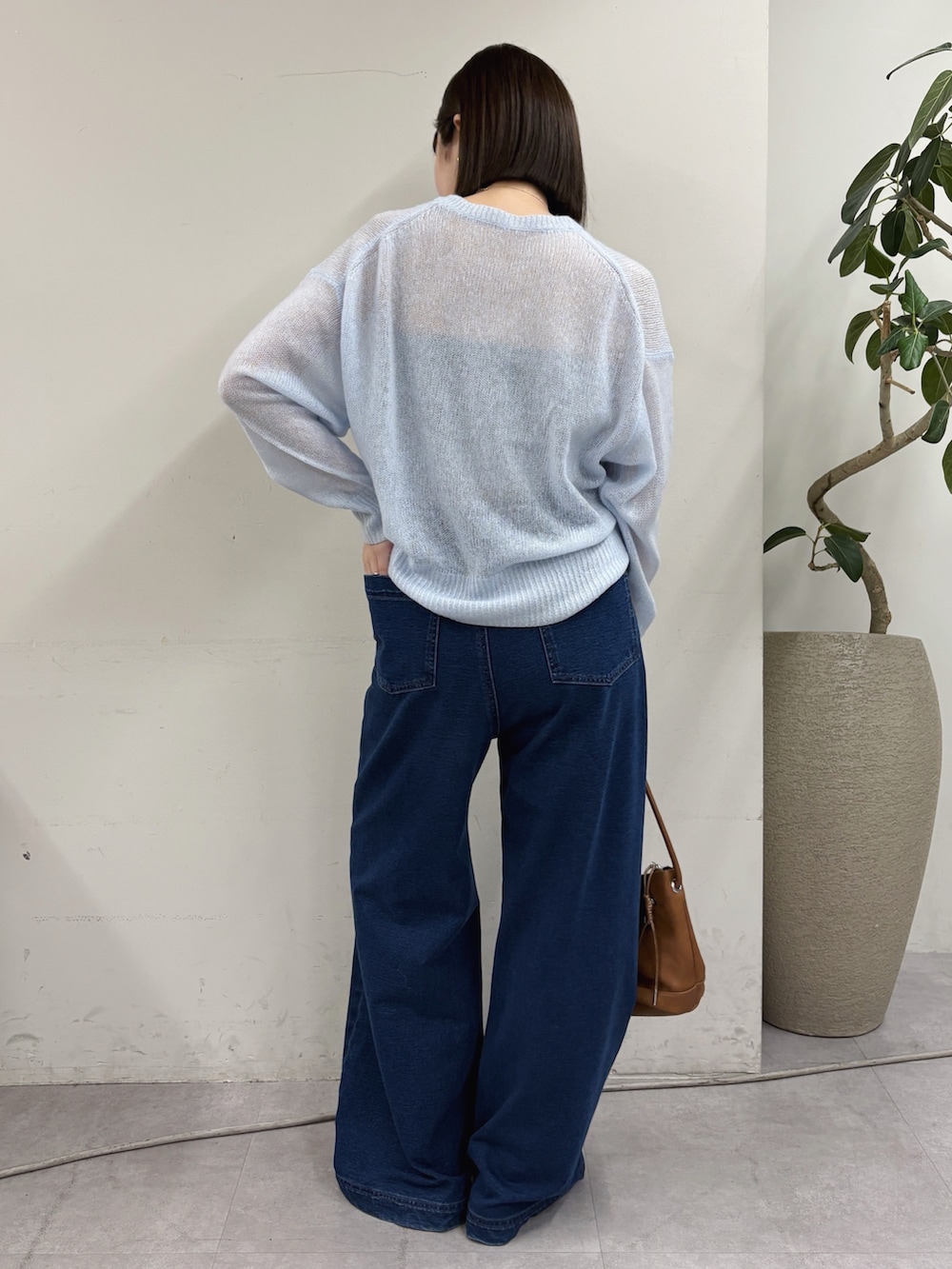 ブルー系のデニムパンツ、ブラック系のパンプス、ホワイト系のニット/セーターを着用したレディースの秋コーディネートの2枚目の写真