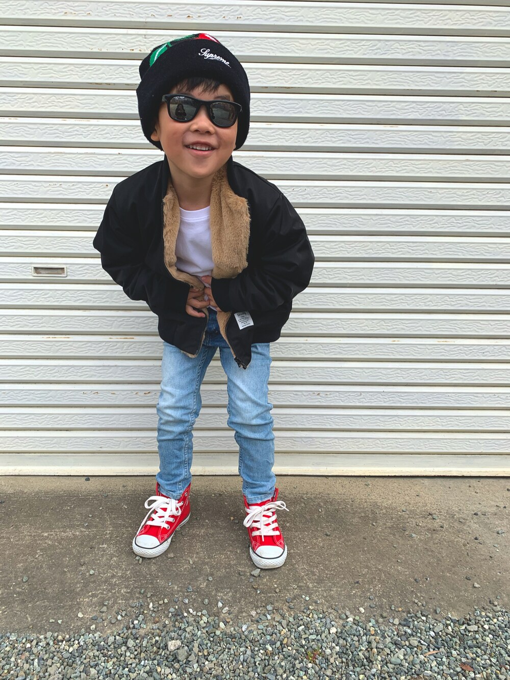 ブラック系のMA-1、ブルー系のデニムパンツ、レッド系のスニーカーを着用したキッズの秋コーディネートの2枚目の写真