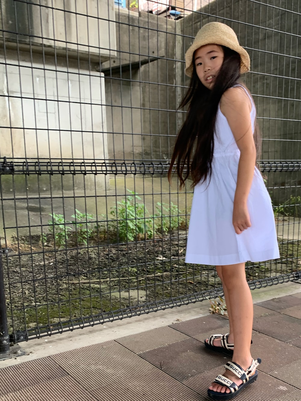 ホワイト系のワンピース、ベージュ系のサンダル、ベージュ系のハットを着用したキッズの夏コーディネートの4枚目の写真