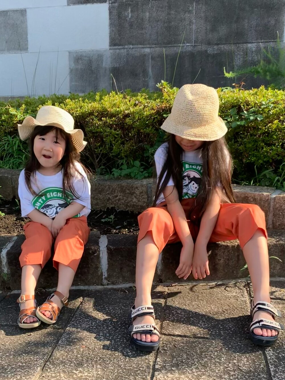 ホワイト系のTシャツ/カットソー、オレンジ系のその他パンツ、ブラウン系のサンダルを着用したキッズの夏コーディネートの2枚目の写真