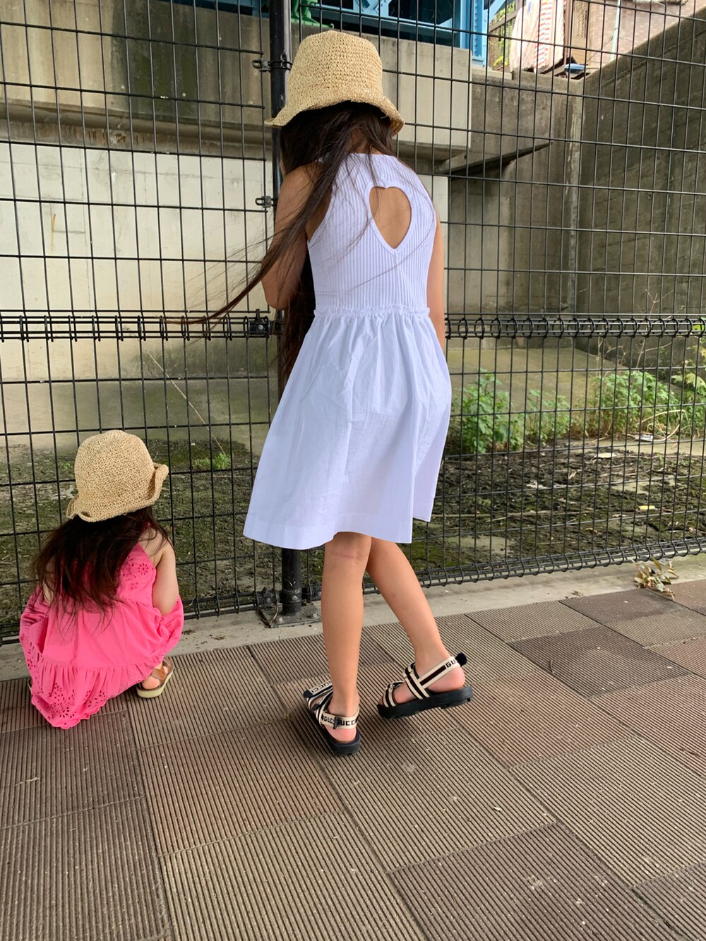 ホワイト系のワンピース、ベージュ系のサンダル、ベージュ系のハットを着用したキッズの夏コーディネートの3枚目の写真