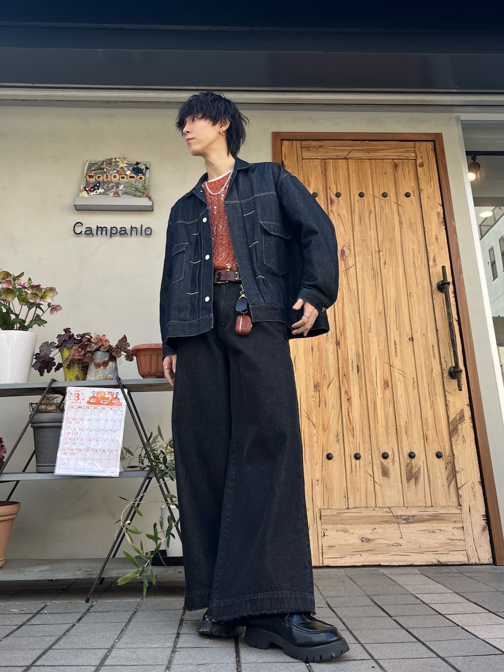 オレンジ系のニット/セーター、ブルー系のセットアップ、ブラック系のデニムパンツを着用したメンズの春コーディネートの2枚目の写真