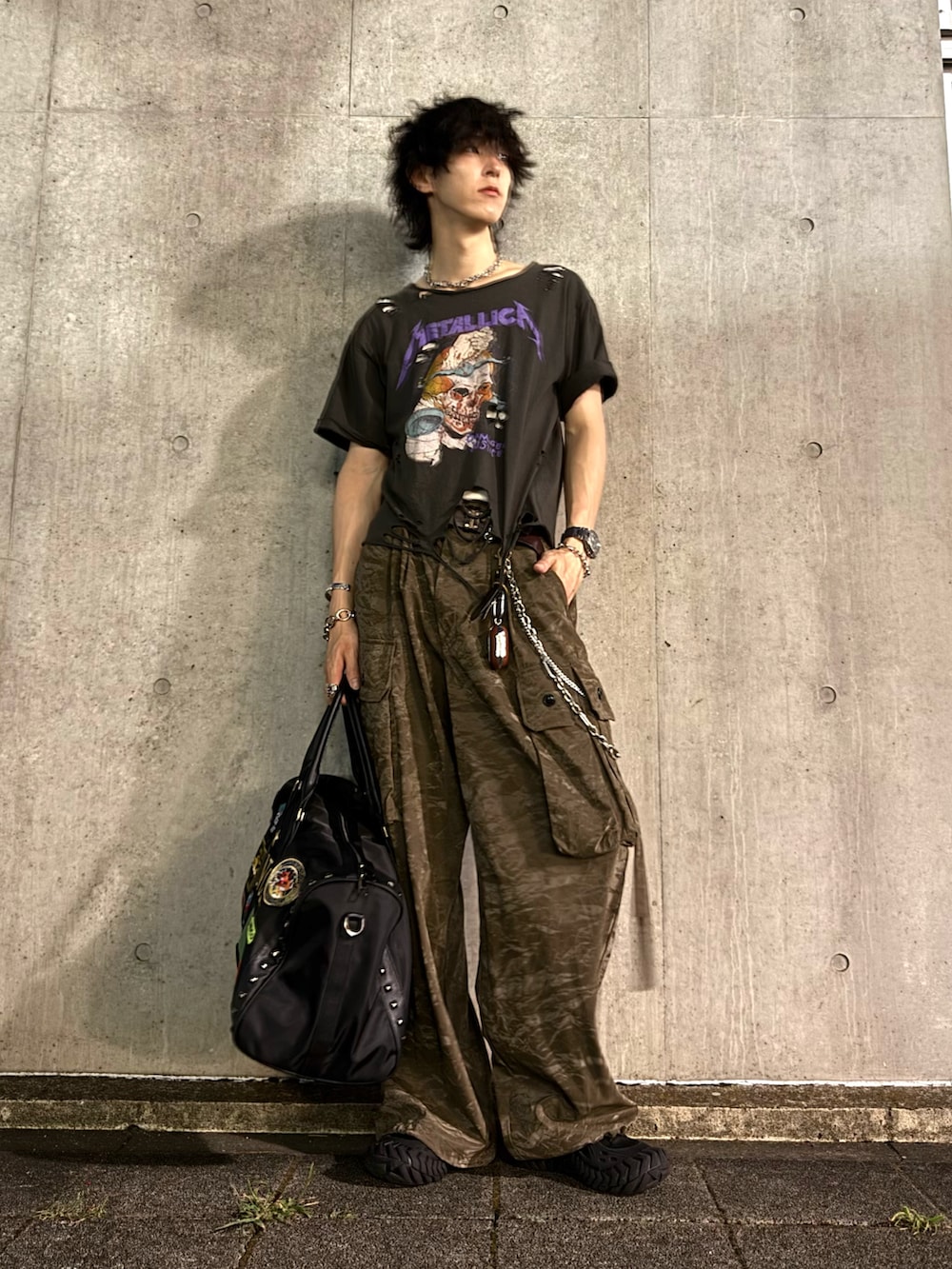 グリーン系のスラックス、ブラック系のスニーカー、グレー系のTシャツ/カットソーを着用したメンズの秋コーディネートの2枚目の写真