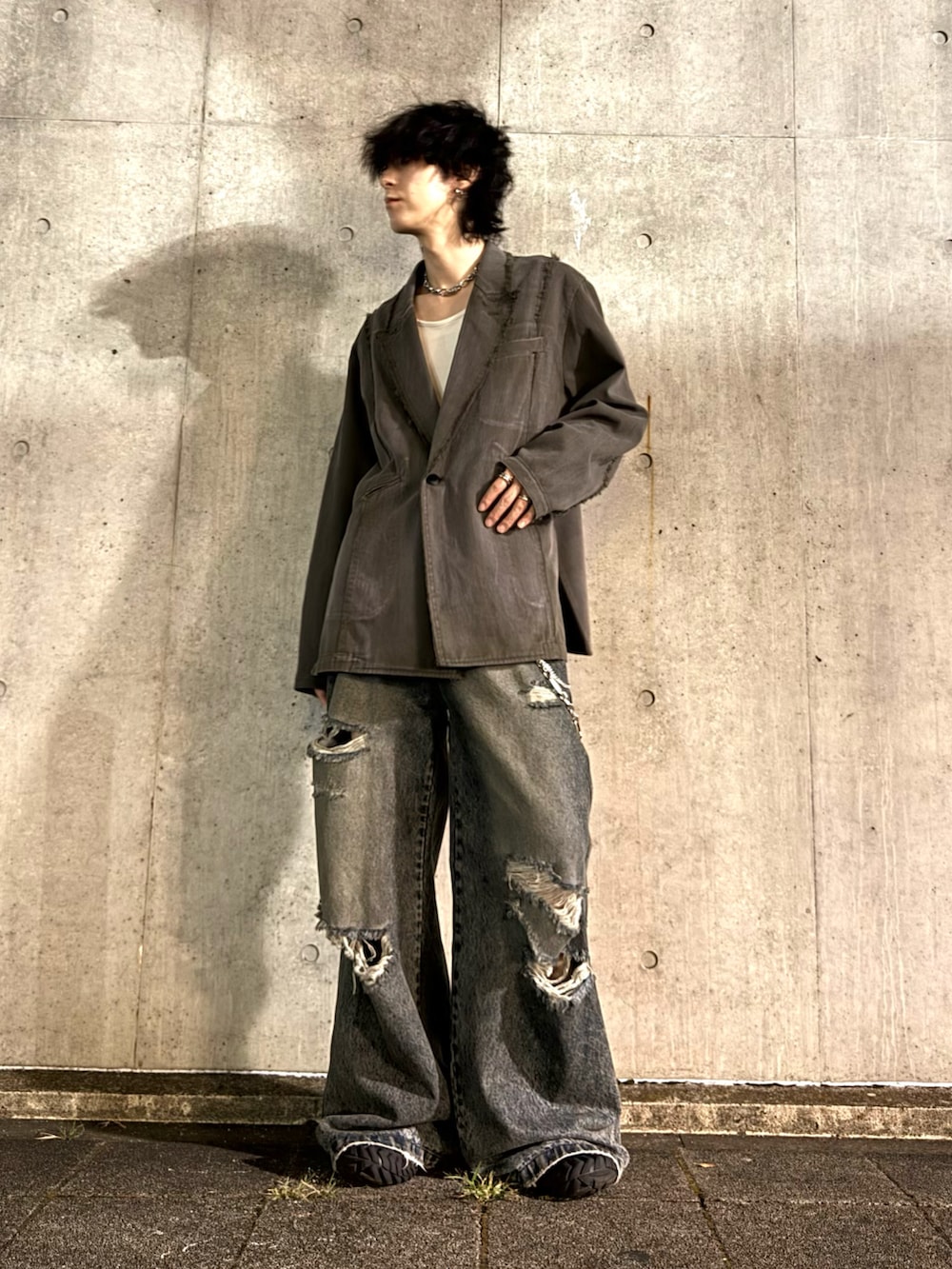 グリーン系のテーラードジャケット、ブルー系のデニムパンツ、ブラック系のスニーカーを着用したメンズの秋コーディネートの2枚目の写真