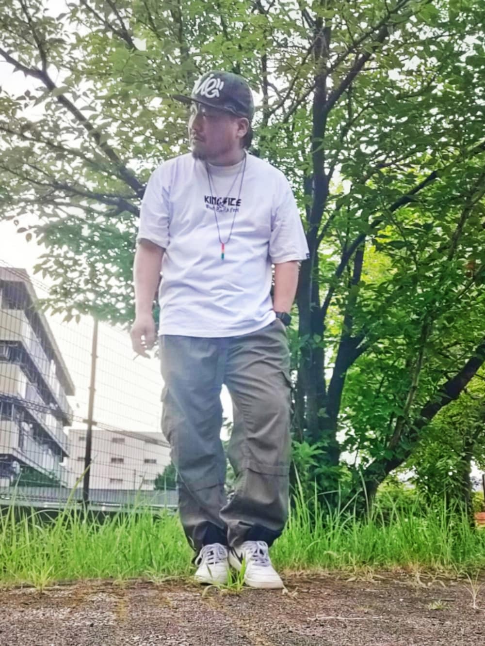 ホワイト系のTシャツ/カットソー、グリーン系のカーゴパンツ、ホワイト系のスニーカーを着用したメンズの夏コーディネートの2枚目の写真