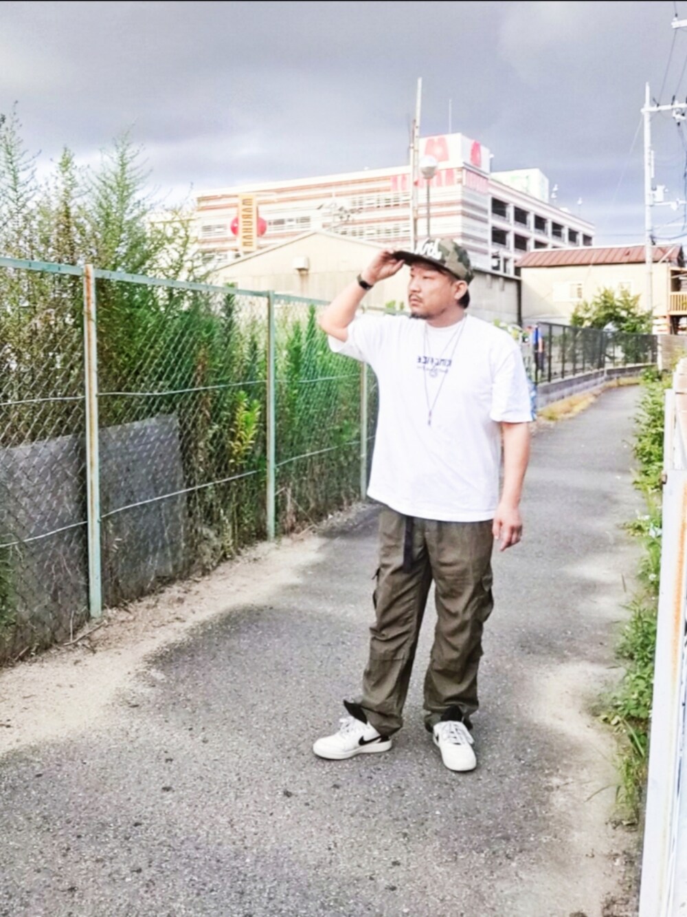 ホワイト系のTシャツ/カットソー、グリーン系のカーゴパンツ、ホワイト系のスニーカーを着用したメンズの夏コーディネートの4枚目の写真