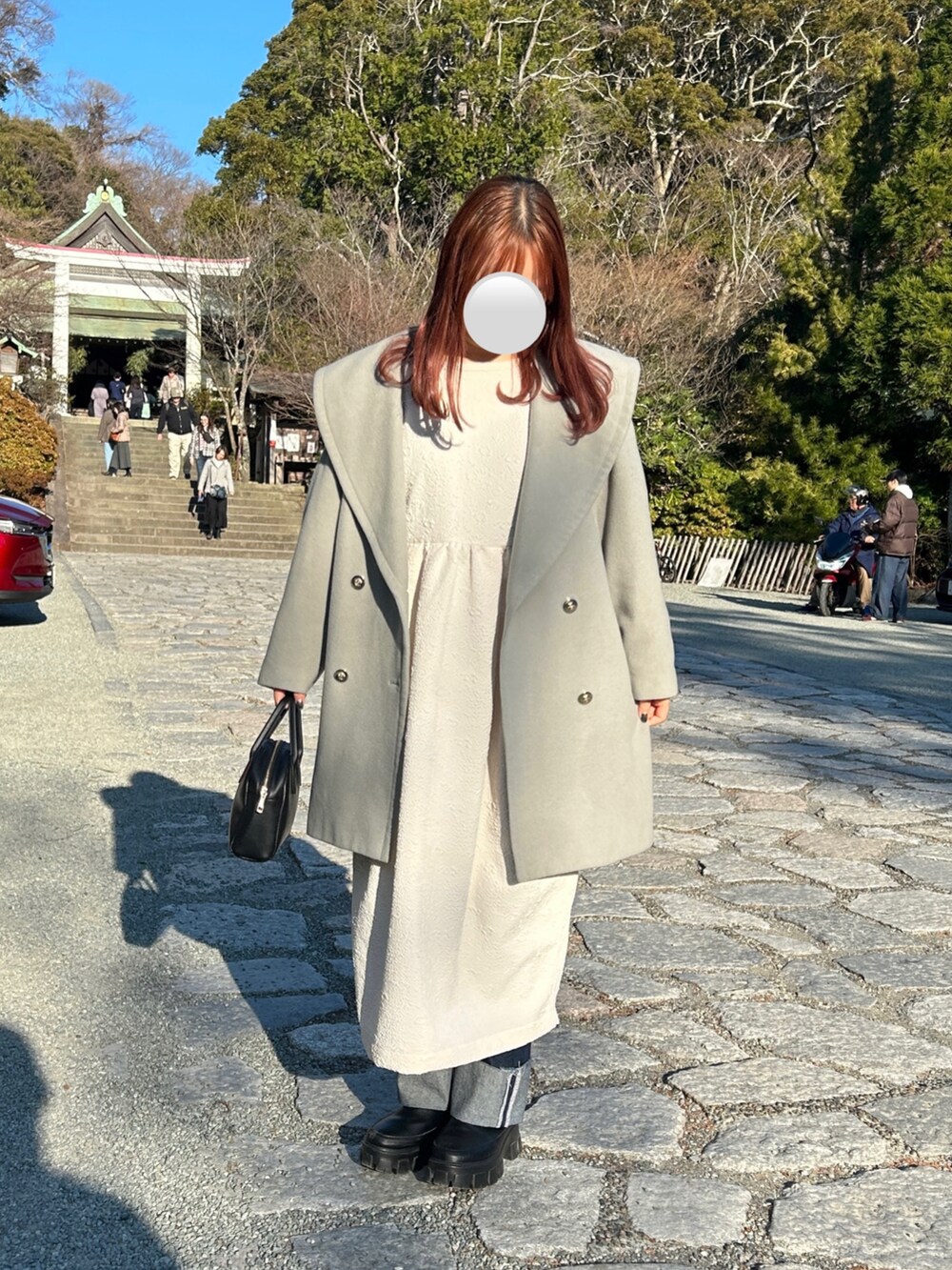 ホワイト系のワンピース、ブルー系のデニムパンツ、ブラック系のブーツを着用したレディースの冬コーディネートの2枚目の写真