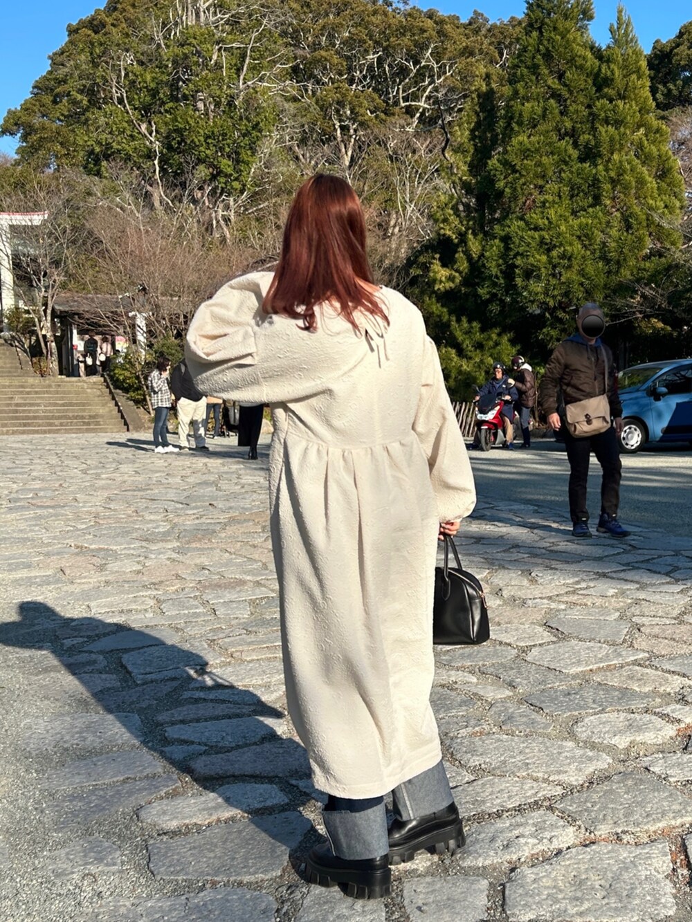 ホワイト系のワンピース、ブルー系のデニムパンツ、ブラック系のブーツを着用したレディースの冬コーディネートの3枚目の写真