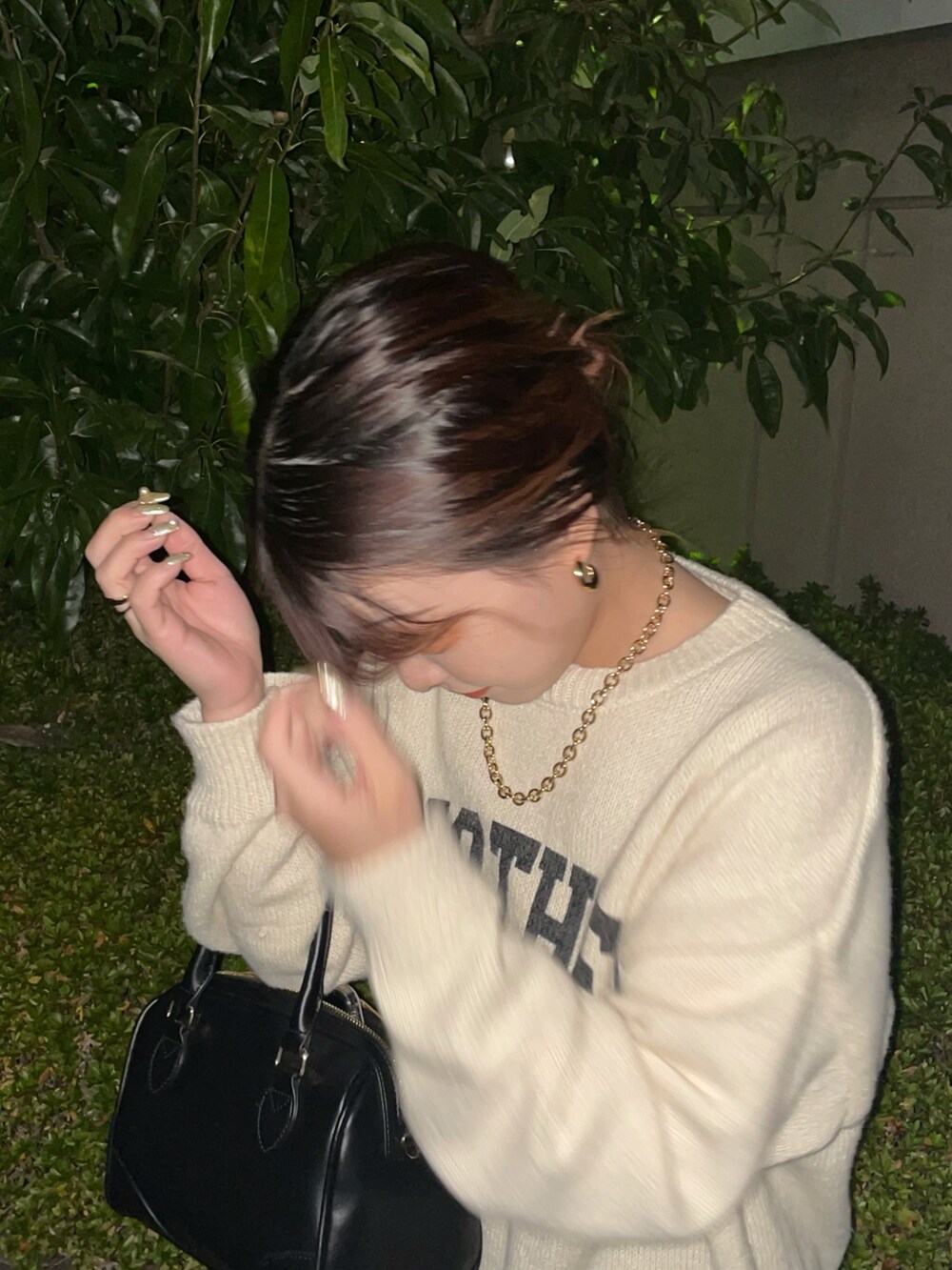 ブラック系のボストンバッグ、ブラック系のスカート、ブラック系のブーツを着用したレディースの秋コーディネートの3枚目の写真