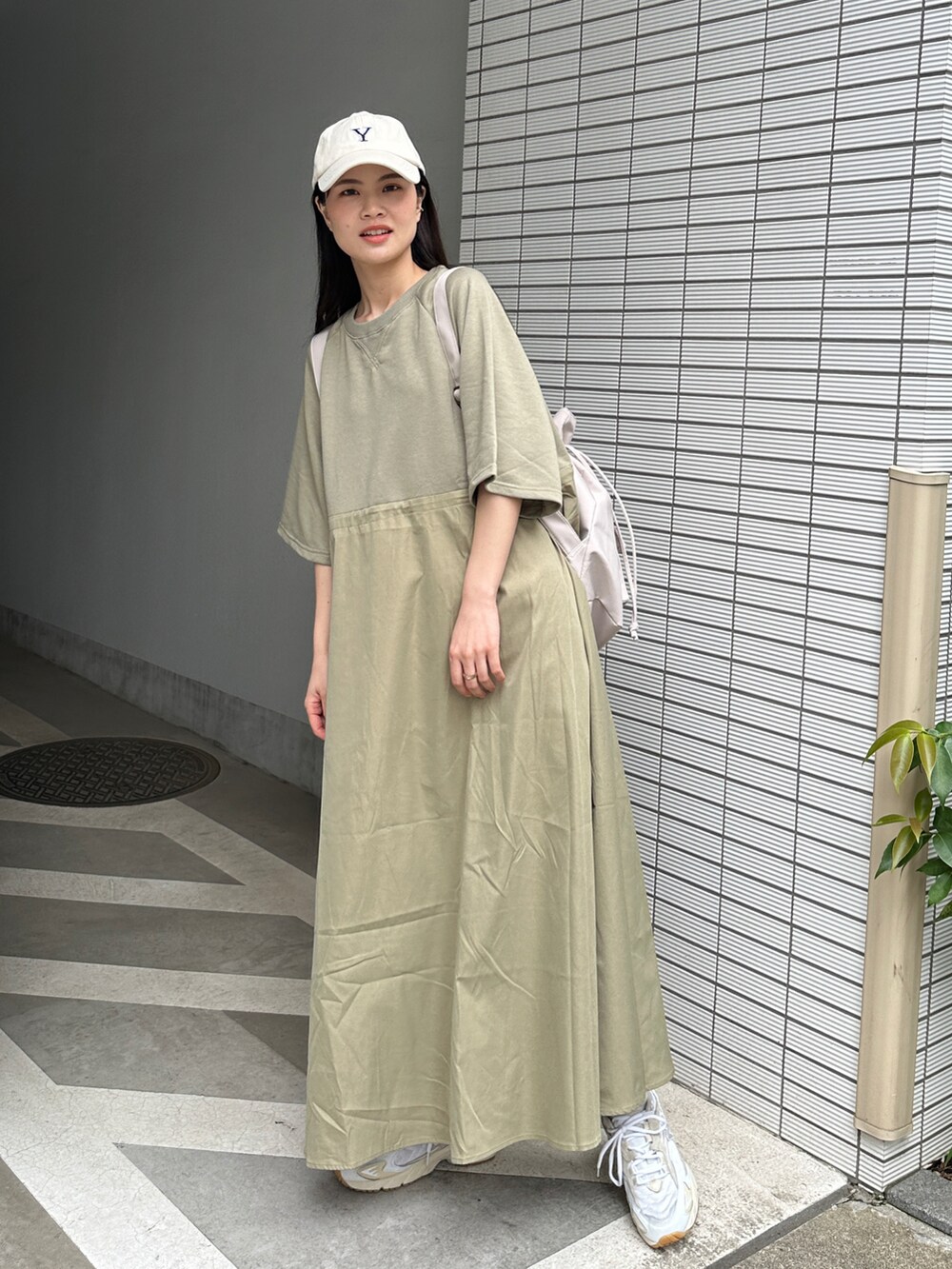 グリーン系のワンピース、ベージュ系のバックパック/リュック、ベージュ系のキャップを着用したレディースの春コーディネートの2枚目の写真