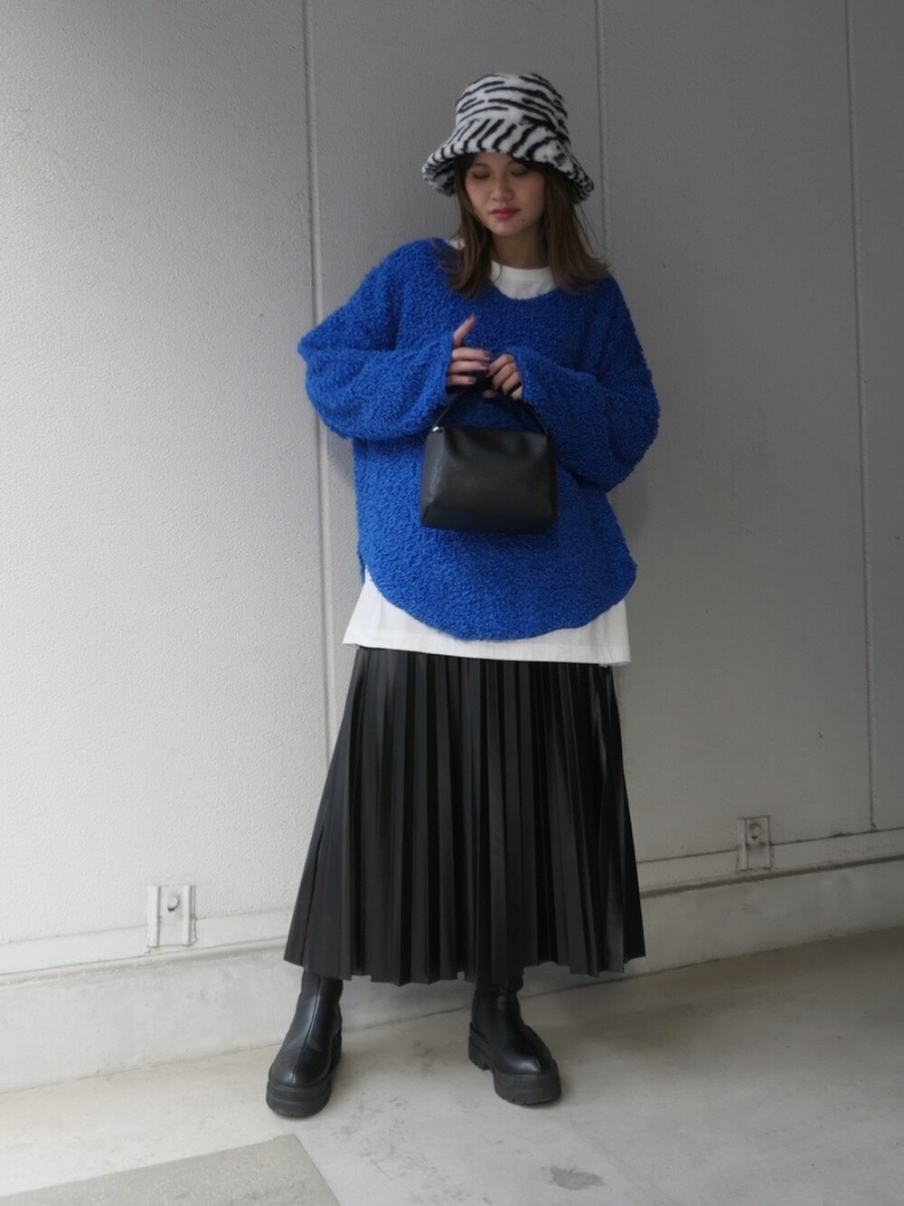 ブルー系のニット/セーター、ベージュ系のTシャツ/カットソー、ブラック系のスカートを着用したレディースの冬コーディネートの2枚目の写真