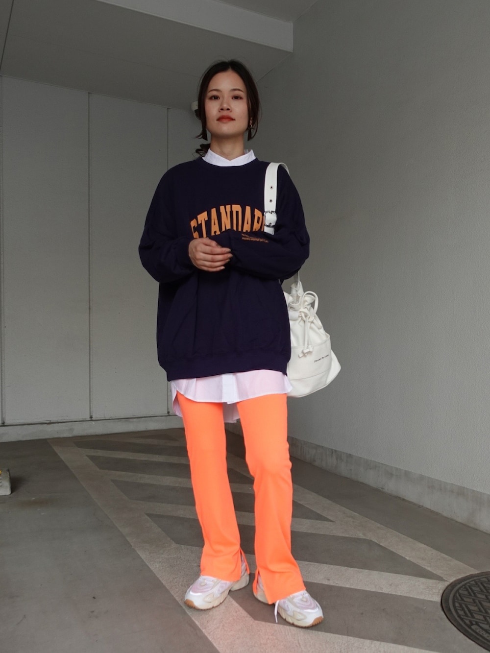 ブルー系のスウェット、オレンジ系のその他パンツ、ホワイト系のトートバッグを着用したレディースの秋コーディネートの2枚目の写真