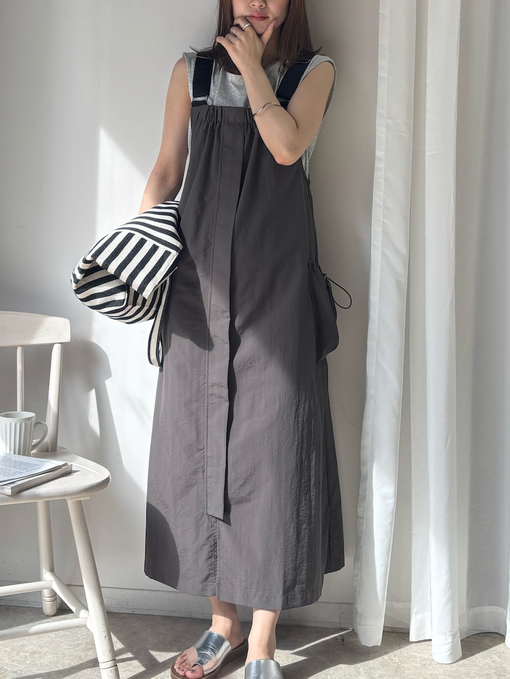 グレー系のジャンパースカート、グレー系のタンクトップ、ブラック系のトートバッグを着用したレディースの夏コーディネートの2枚目の写真