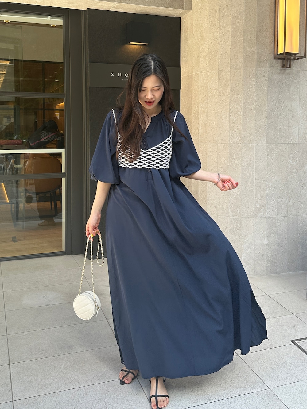 ブルー系のワンピース、ホワイト系のベスト、ホワイト系のショルダーバッグを着用したレディースの春コーディネートの3枚目の写真