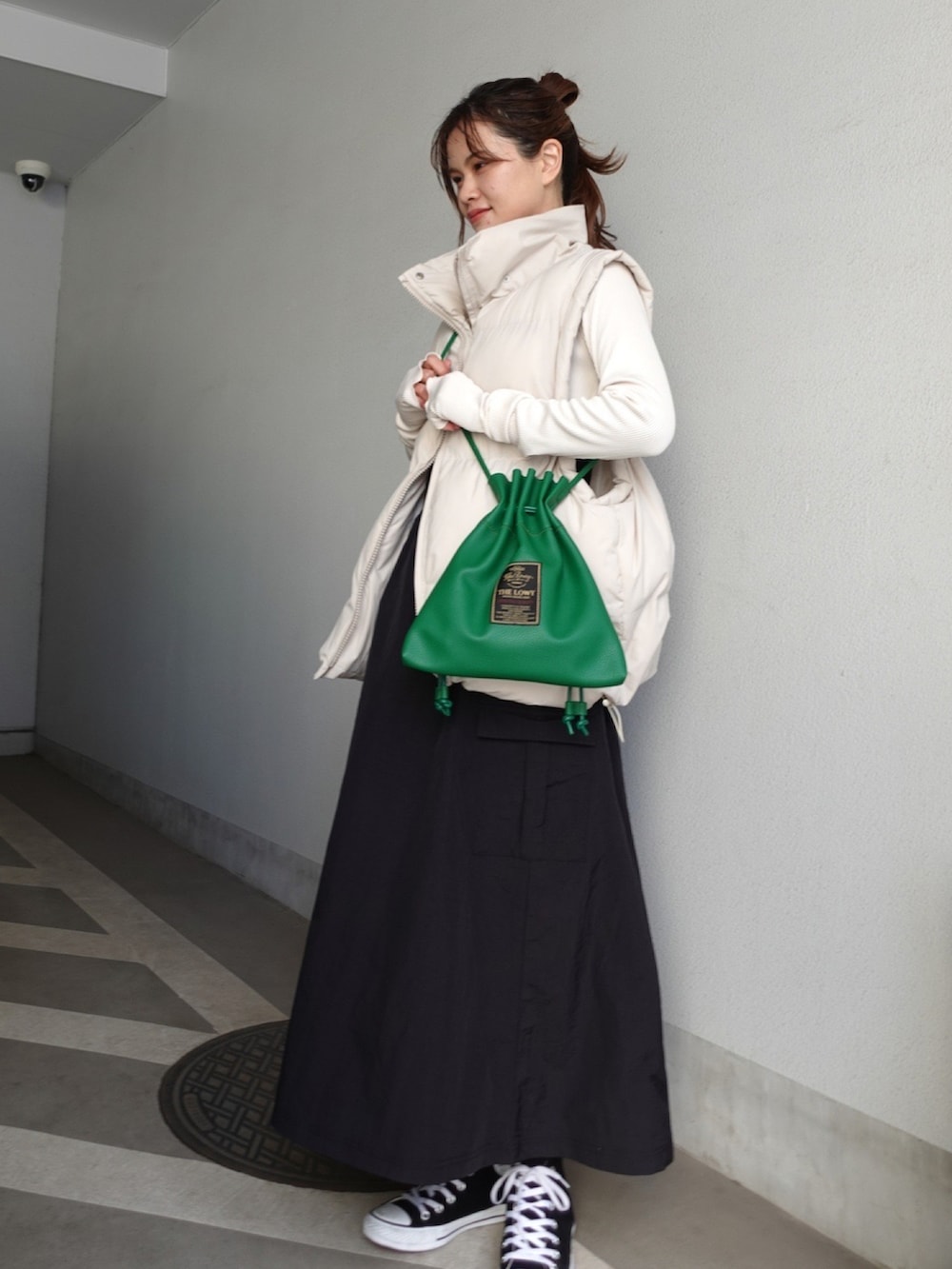 ブラック系のワンピース、グリーン系のショルダーバッグ、ベージュ系のダウンベストを着用したレディースの冬コーディネートの2枚目の写真