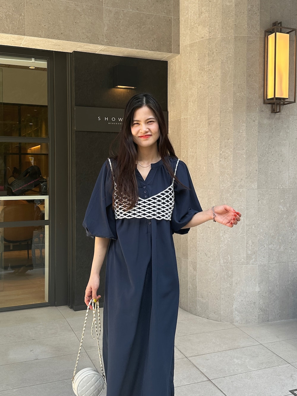 ブルー系のワンピース、ホワイト系のベスト、ホワイト系のショルダーバッグを着用したレディースの春コーディネートの2枚目の写真