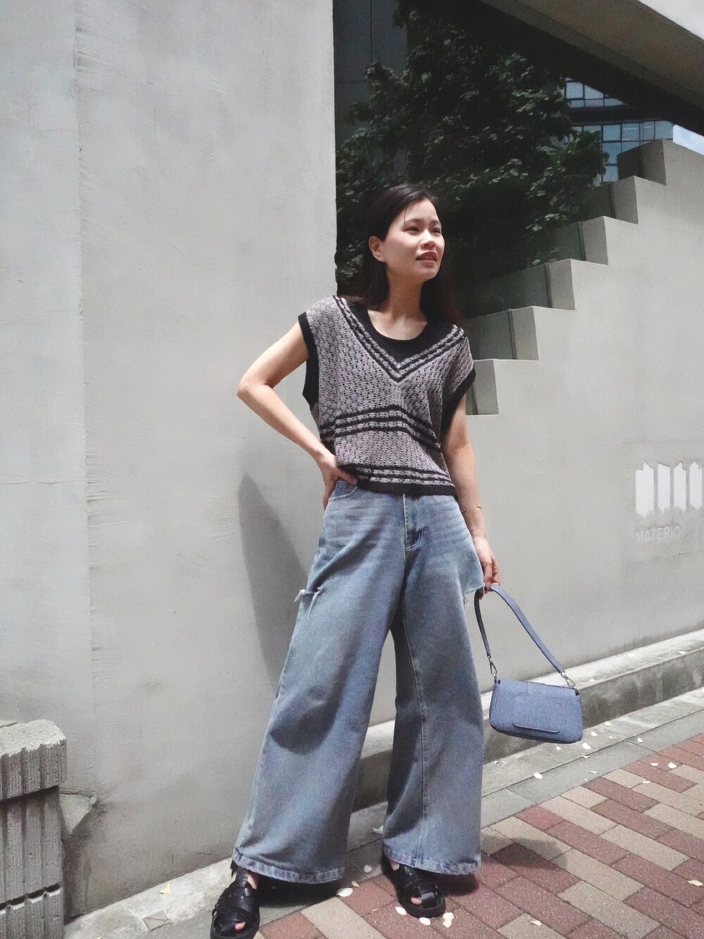グレー系のベスト、ブルー系のデニムパンツ、ブルー系のショルダーバッグを着用したレディースの夏コーディネートの2枚目の写真