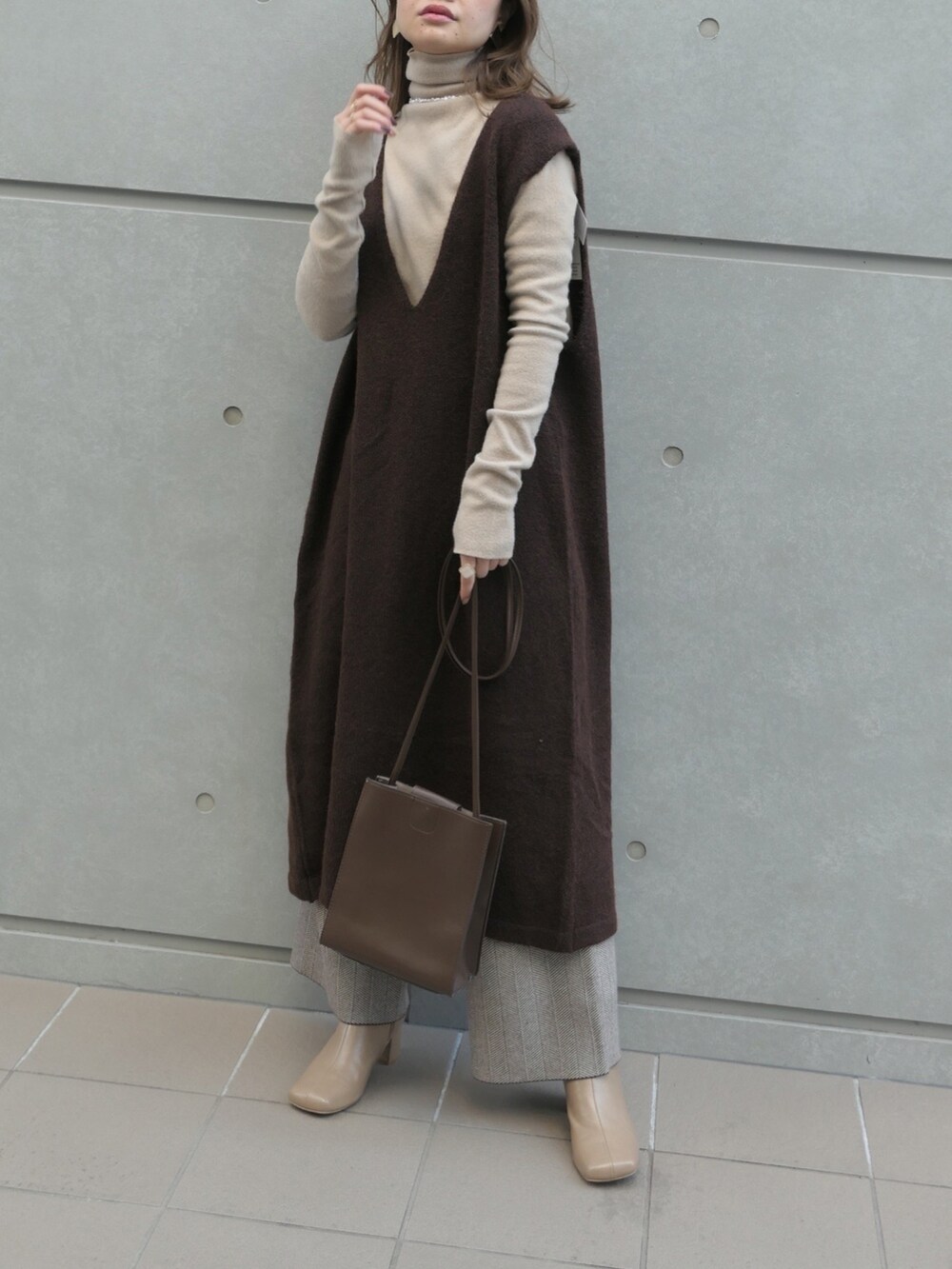 ブラウン系のショルダーバッグ、ブラウン系のワンピース、ベージュ系のTシャツ/カットソーを着用したレディースの秋コーディネートの2枚目の写真