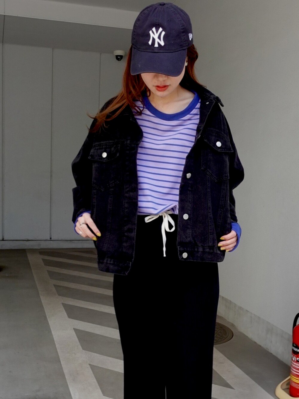 ブラック系のデニムジャケット、パープル系のTシャツ/カットソー、ブラック系のスウェットパンツを着用したレディースの春コーディネートの2枚目の写真