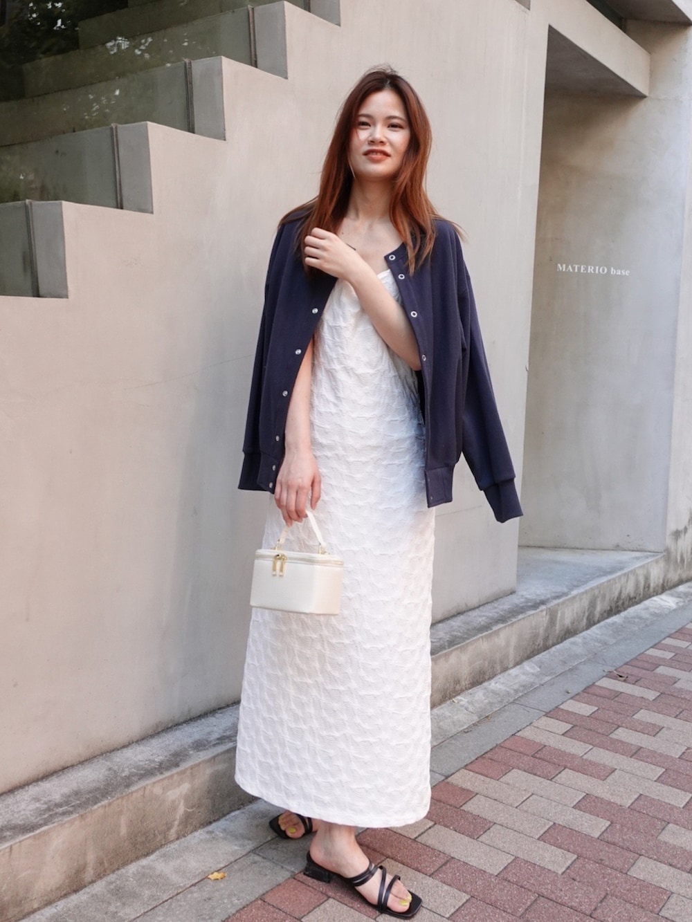 ブラック系のスウェット、ホワイト系のワンピース、ホワイト系のショルダーバッグを着用したレディースの春コーディネートの2枚目の写真